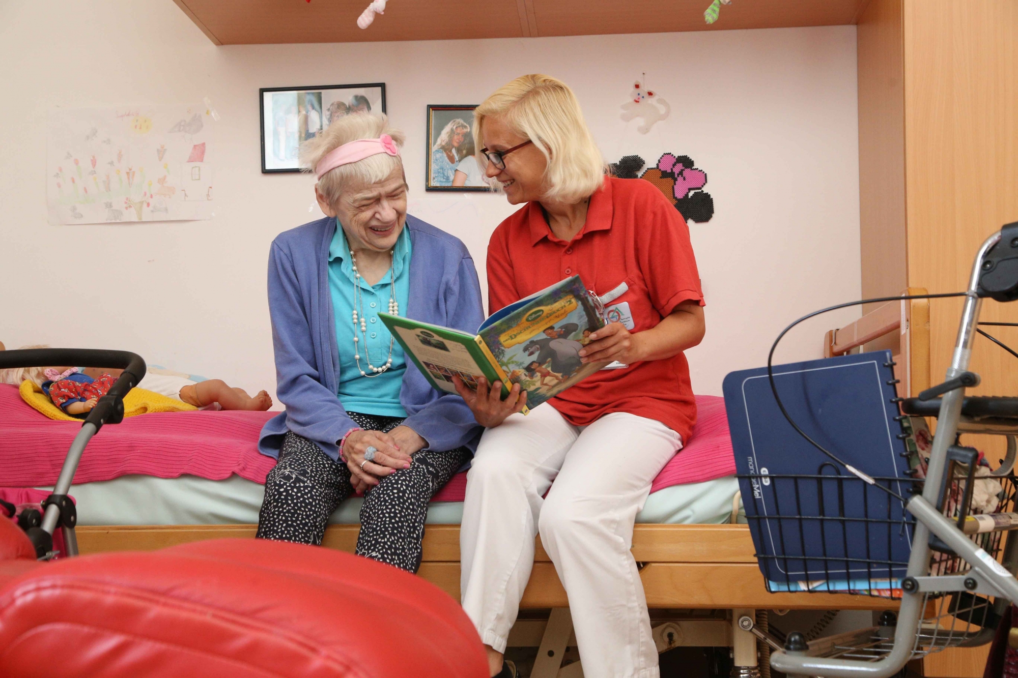 Bewohnerin liest Buch mit Pflegeperson